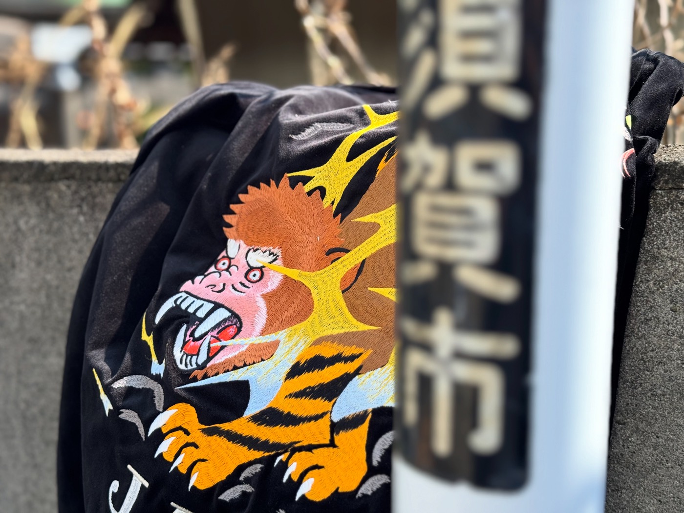 横須賀市の街路標識のそばに掛けたオリジナルスカジャン。背中に鵺（ぬえ）の刺繍